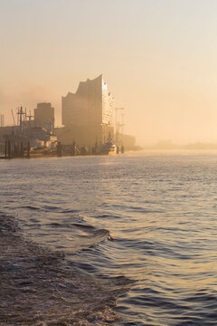 Germany, Hamburg, Silhouette of Elbphilharmonie seen across river at sunrise
