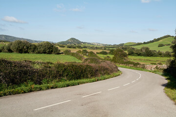 Empty road amidst green landscape against sky during sunny day, Spain