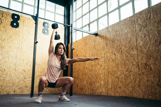 Young woman doing dumbbell exercise at gym
