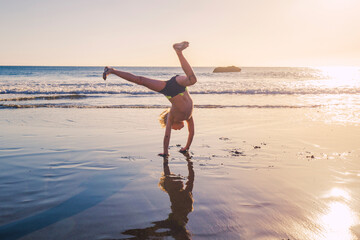 Little boy practicing handstand on the beach
