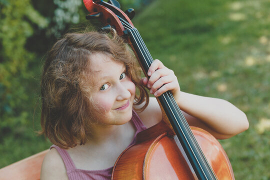 A smiling girl with the cello in garden
