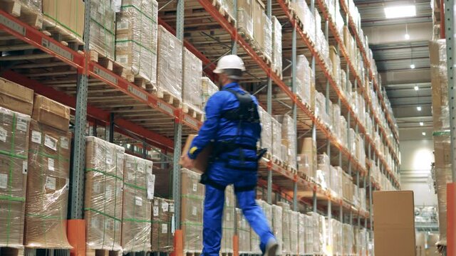 Storage employee is using ergoskeleton to carry the boxes