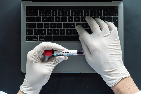 Doctor analyzing COVID-19 sample while typing on laptop at desk in laboratory