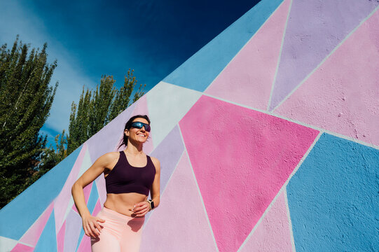 Mature woman running in front of a colorful wall