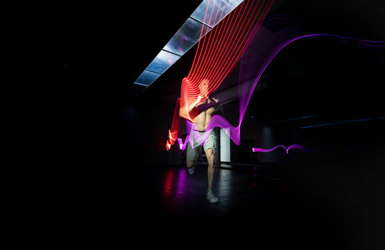 Athlete running in dark area surrounded by colored lights