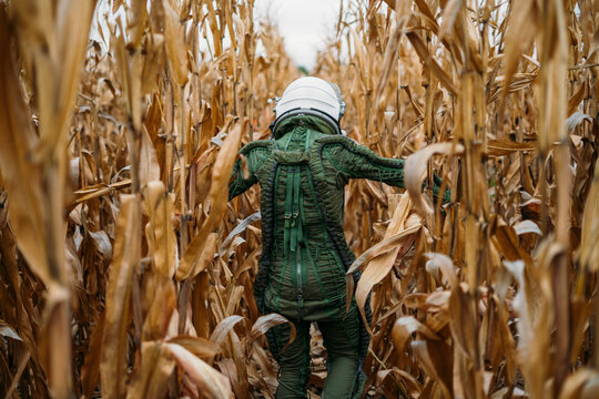 Young spaceman walking through corn field
