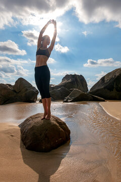Seychelles, Mahe, Takamaka Beach, woman doing yoga on a rock