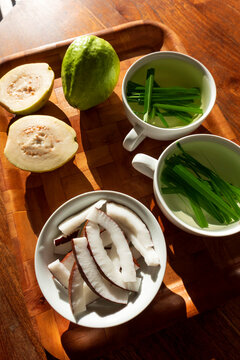 Seychelles, wooden tray with guava, bowl of fresh coconut slices and cups of lemongrass tea