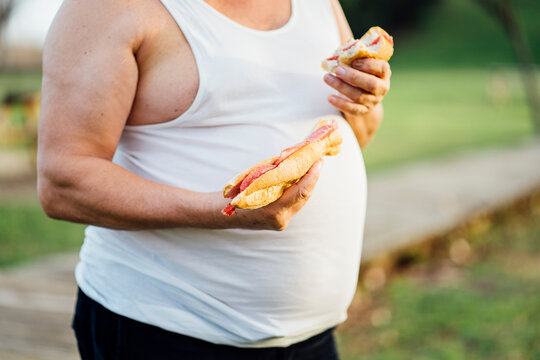 Man with beer belly holding sandwich