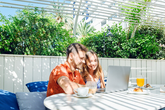 Cheerful young couple using laptop during breakfast