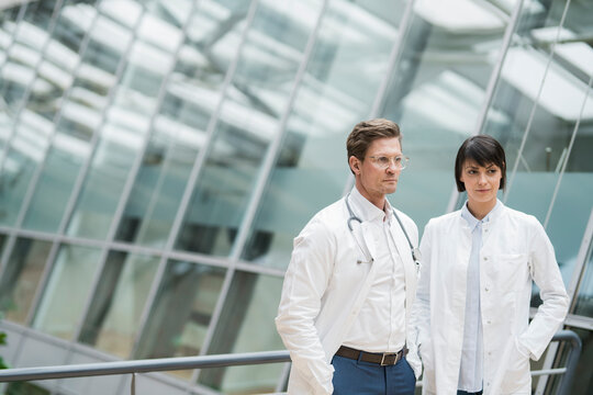 Two pensive doctors standing in atrium