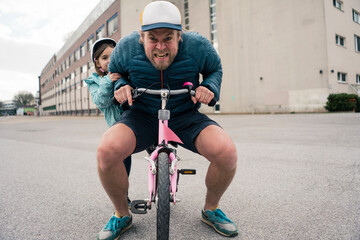 Playful father with daughter on her bicycle