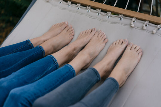 Feet of three females lying in hammock in garden