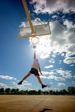 Man playing basketball on yellow court, dunking