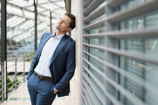 Businessman relaxing with eyes closed, leaning on wall