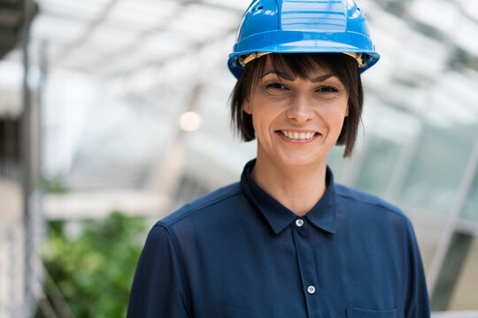 Female architect wearing blue hard hat, portrait
