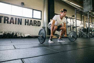 Male athlete lifting deadlift while exercising in gym