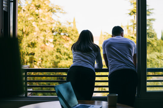 Couple leaning on balcony railing while standing at home