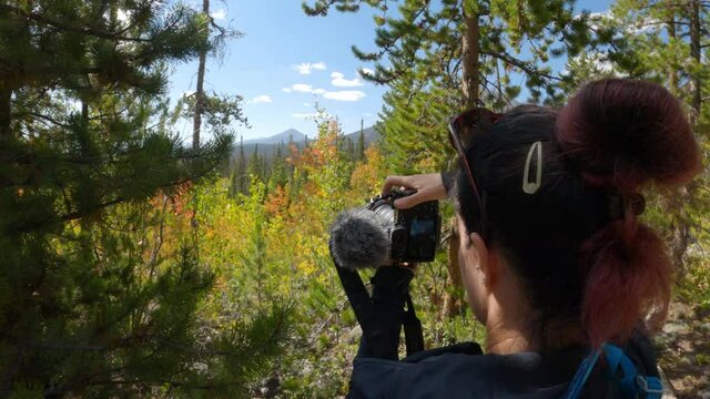 Female taking pictures of mountains and leaves changing colors, handheld
