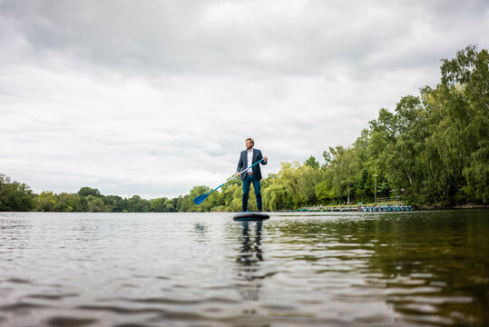 Businessman stand up paddling on a lake