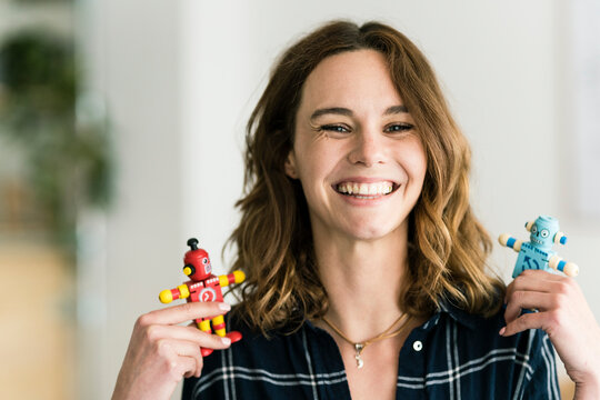 Laughing woman holding male and female toy robots
