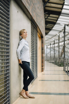Young businesswoman leaning against a wall in a modern office building
