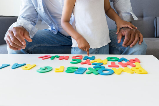 Close-up of father and daughter playing with alphabet learning game at home
