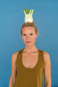Smiling blond woman with fennel, blue background