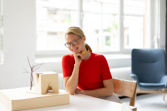 Young woman in office with architectural model on desk