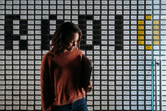 Young woman holding laptop at a wall with the word 'radio'