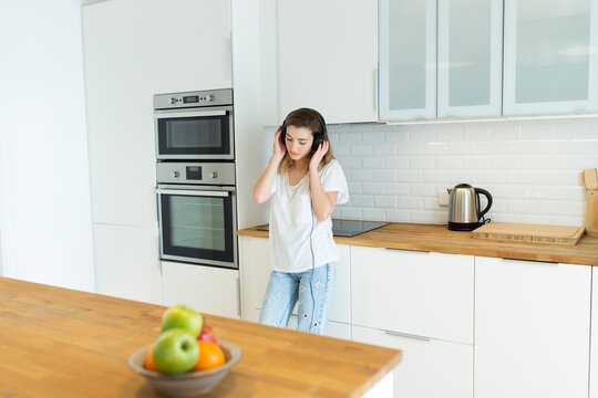 Female teeanger with headphones in the kitchen