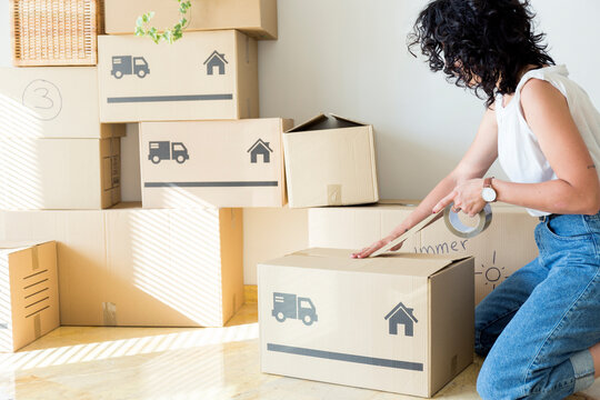 Young woman moving out taping cardboard box