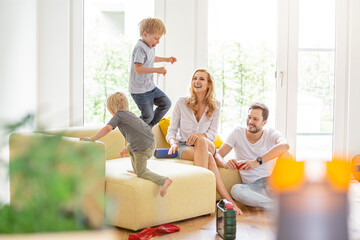 Happy family in living room of their new home with boys romping about