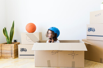 Girl inside cardboard box at new home closing bicycle helmet
