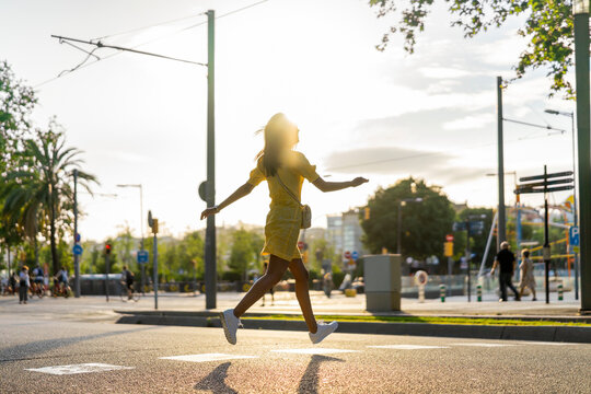 Young woman running on city street during sunny day