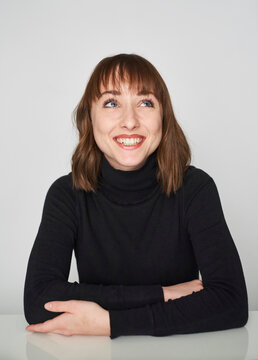 Portrait of smiling young woman wearing black turtleneck pullover looking up