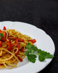 Close-up of part of rice noodle dish with soy sauce, curry, red bell peppers, parsley and tofu....