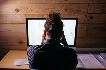 Rear view of young architect working hard on a new project at home at night