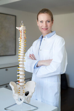 Portrait of confident female doctor in medical practice with spine column