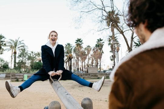 Exuberant couple on a seesaw at a playground