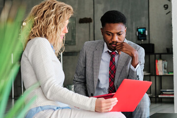 Thoughtful businessman looking at strategy on digital tablet while sitting by female colleague