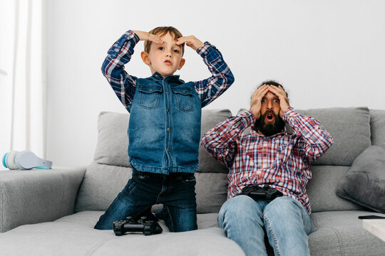 Portrait of father and son together on the couch playing computer game