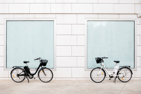 Two e-bikes at a white wall with two windows