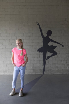 Portrait of laughing blond girl and shadow of ballerina in the background