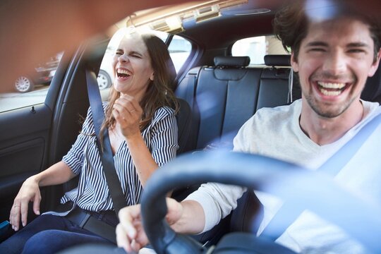 Laughing couple in a car with man driving
