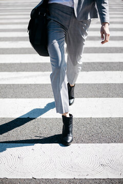 Business woman walking on zebra crossing, low section