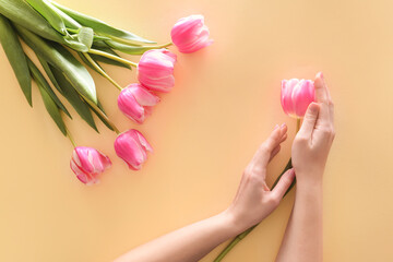 Female hands with beautiful fresh flowers on color background