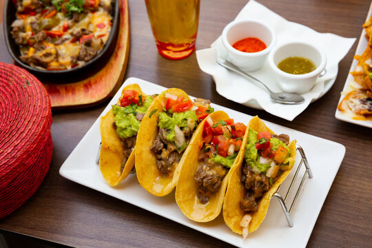Mexican food tasty tacos with beef, guacamole sauce and vegetables