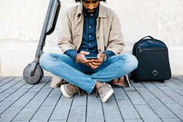 Man sitting on his E-Scooter using mobile phone