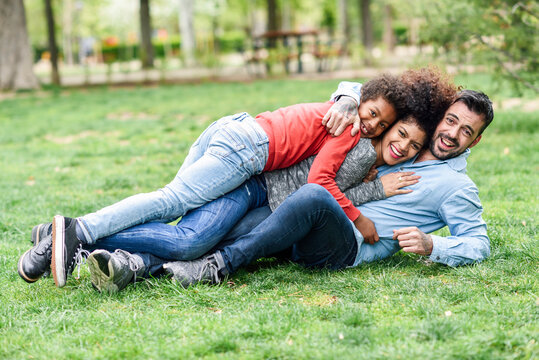 Happy family embracing, lying on grass in a park